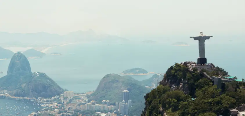 Imagem de trás do Cristo Redentor e parte da cidade do Rio de Janeiro ao fundo