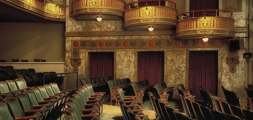 Imagem interna do Teatro, com as poltronas verdes.